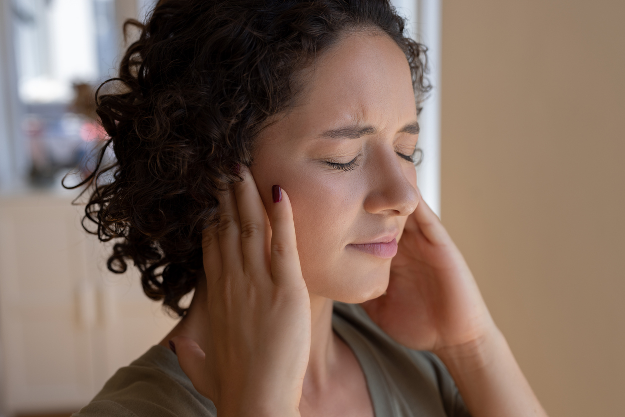 Woman holding her ears to block out tinnitus